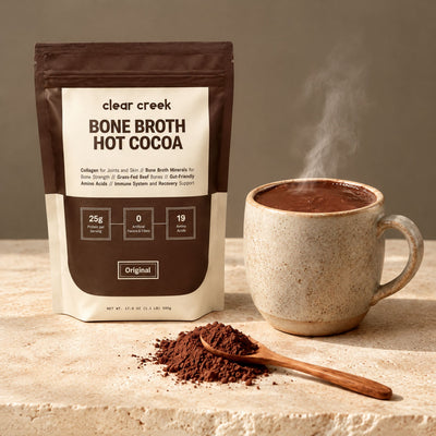 The Clear Creek pouch on a stone slab beside a steaming mug of thick hot cocoa and a spoon of cocoa powder